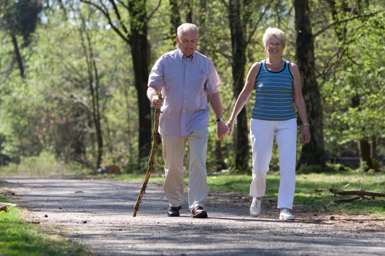 Elderly couple walking through the park hand in hand