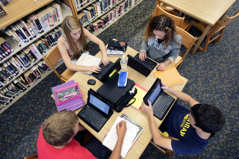 Clark Mjelstad, bottom left, Autumn Gossett, Jackie Harmon and Alex Kramlich work on their tablets on Sept. 4, 2013, in the library at Fargo North Hig...