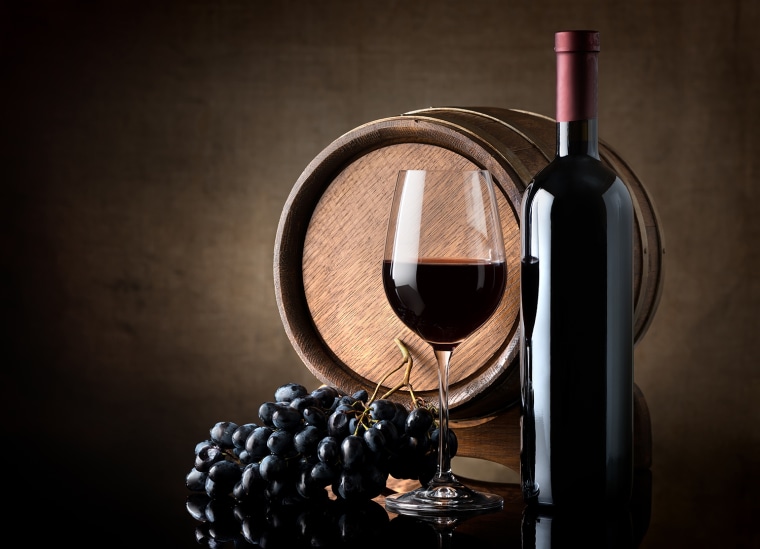 Bottle of red wine, grapes and wooden barrel