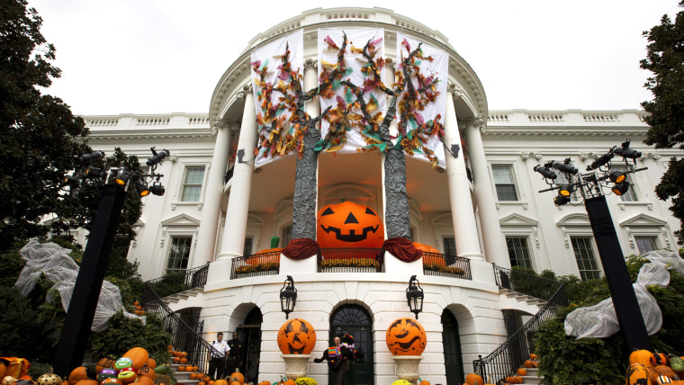 A White House usher takes a model of one of the Obama dogs outside as Halloween decorations adorn the South Portico of the White House in Washington, ...