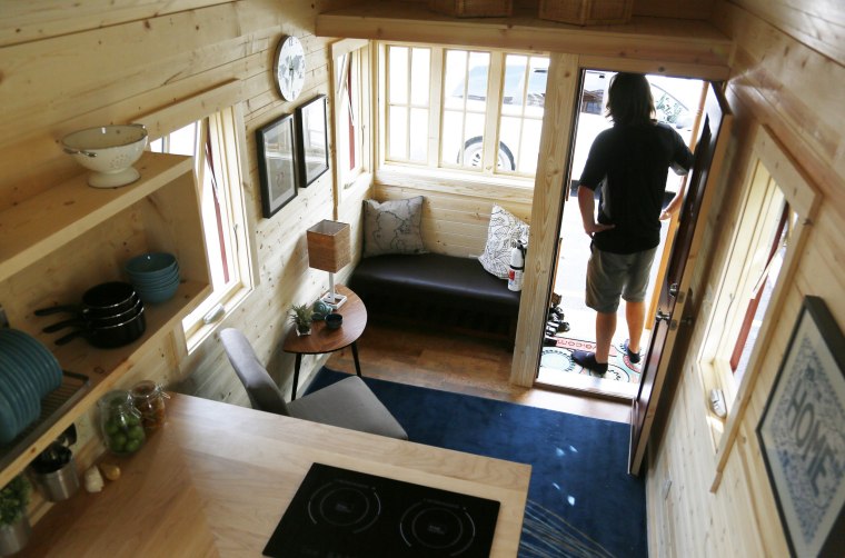 Living tiny can be a challenge with more than one person. Here, Guillaume Dutilh, a Tumbleweed workshop host, poses on the porch of a Tumbleweed brand Cypress 24 model Tiny House on display in Boulder, Colorado, on Aug. 4, 2014.