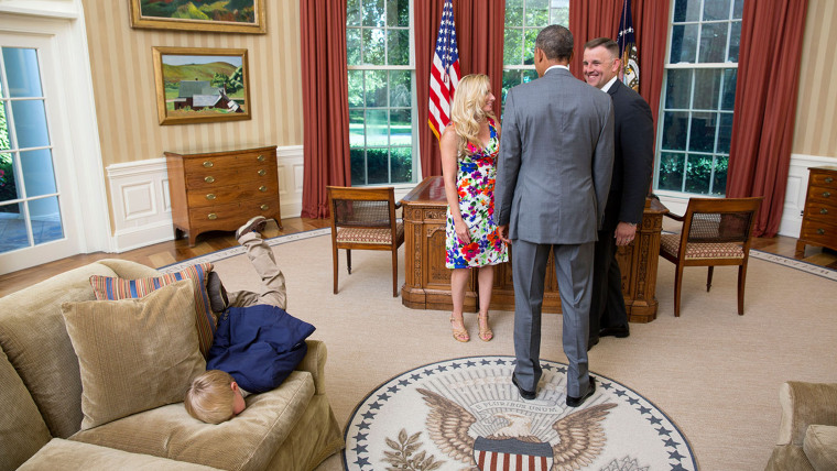 President Barack Obama visits with a departing United States Secret Service agent and his wife as their son dives into a couch in the Oval Office, Jun...
