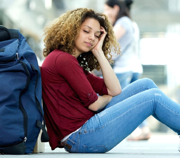 Image: Tired young woman sleeping at airport with luggage