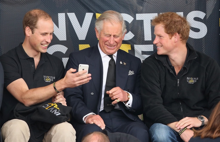 LONDON, ENGLAND - SEPTEMBER 11:  Prince William, Duke of Cambridge, Prince Harry and Prince Charles, Prince of Wales look at a mobile phone as they wa...