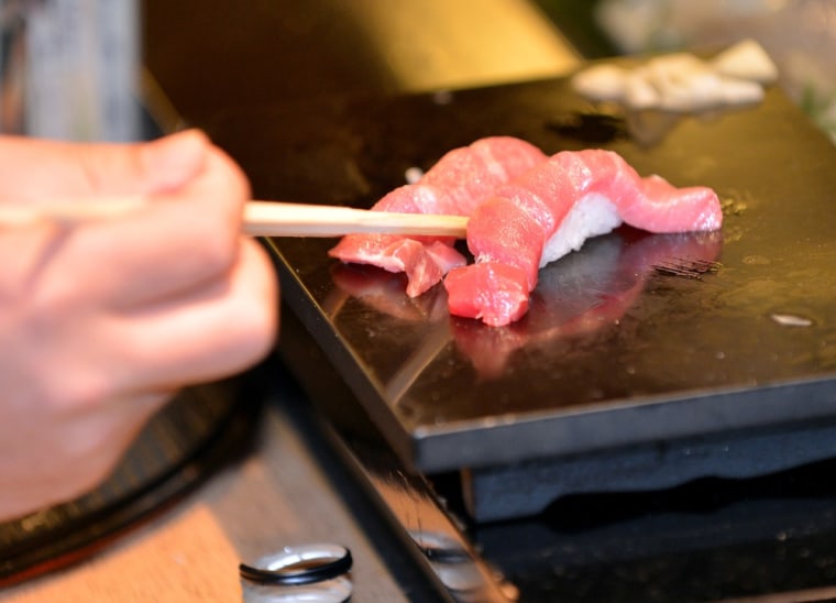 A customer selects a piece of fat tuna sushi made from a 222-kg (488-pound) bluefin tuna, purchased earlier in the day for a record price and sliced u...