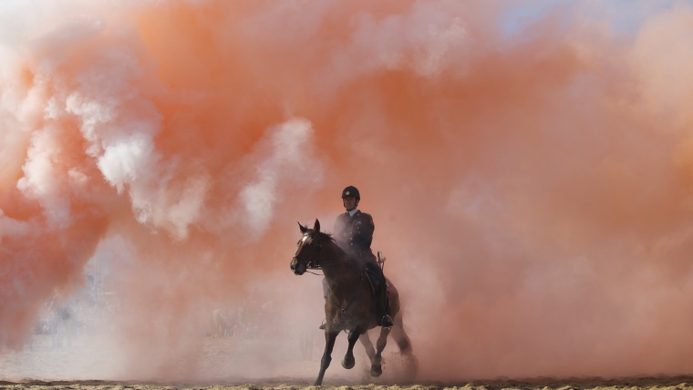 Smoke from grenades shrouds horses and riders during a practice session for members of the Dutch cavalry in Scheveningen, Netherlands, Monday, Sept. 1...