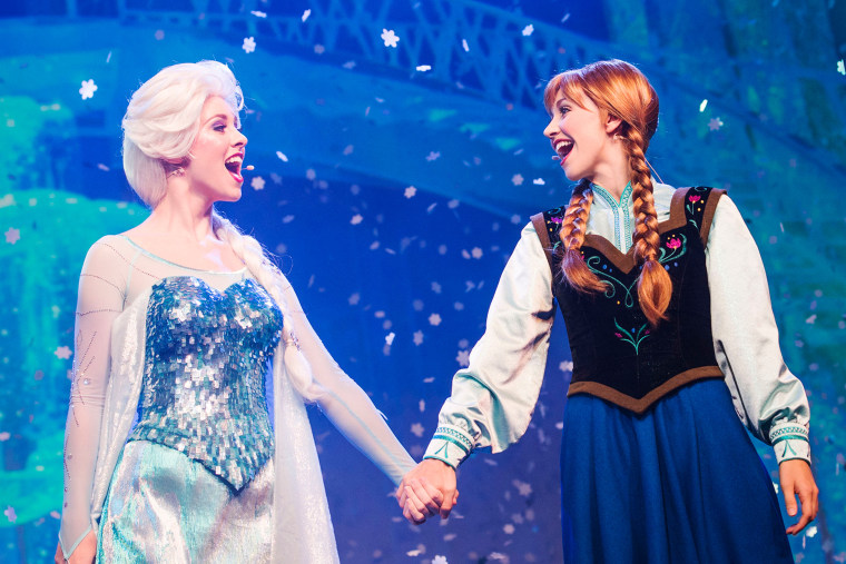 Actors playing Elsa and Anna sing at a Disney show.