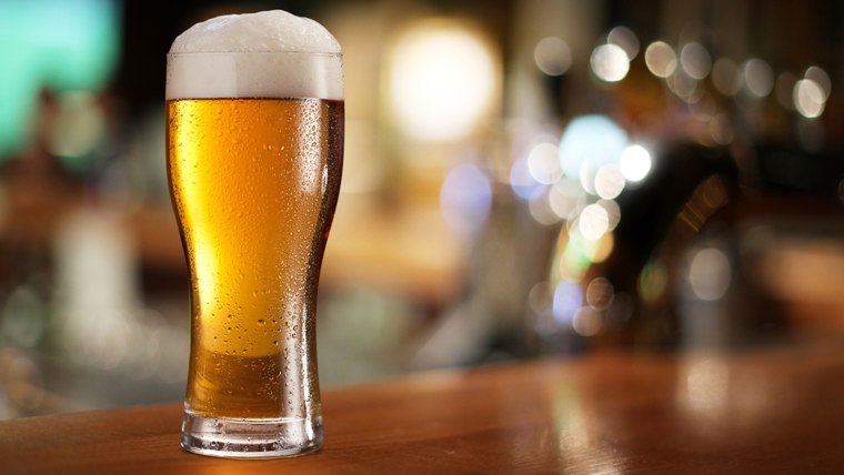 Glass of light beer on a dark pub.; Shutterstock ID 120711982; PO: today.com