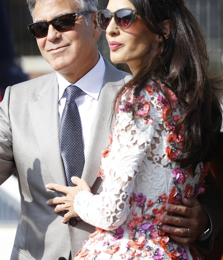 George Clooney is flanked by his wife Amal Alamuddin as they leave the Aman luxury Hotel in Venice, Italy, Sunday, Sept. 28, 2014.