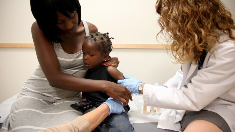 Shakeithia Roberts holds her son, Jermaine Roberts getting a measles shot.