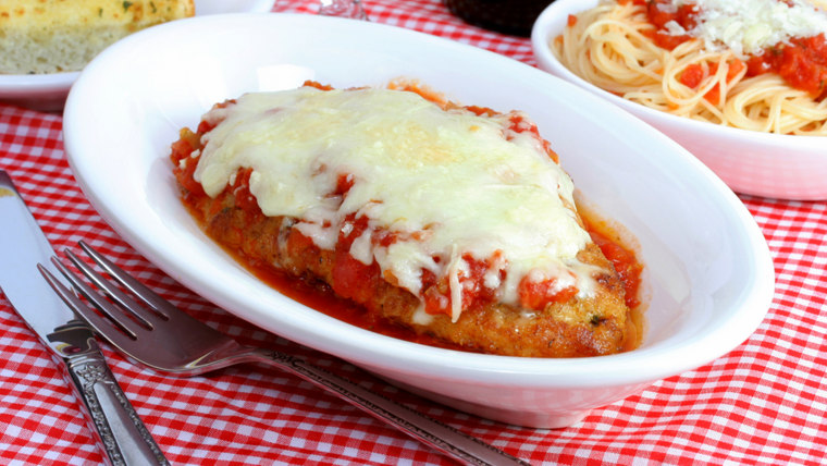 Chicken parmigiana with sides of spaghetti and garlic bread in individual plates.; appetizing; baked; bowl; bread; checked; cheese; chicken; close-up;...