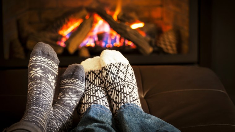 Feet in wool socks warming by cozy fire; Shutterstock ID 142464652; PO: today.com