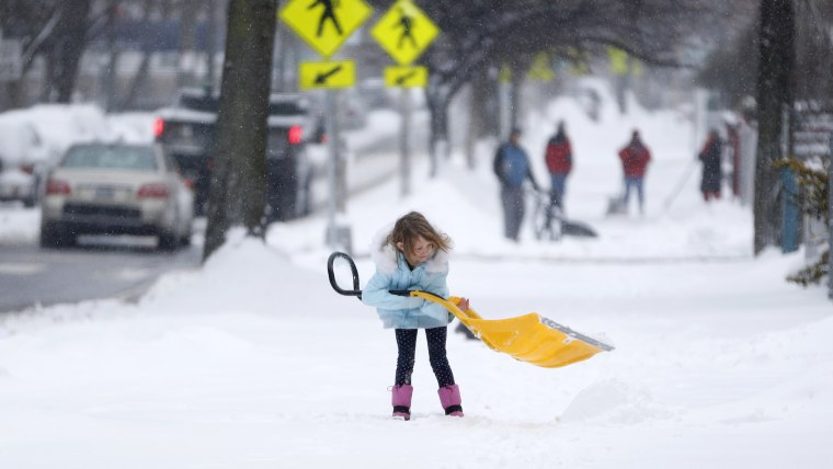 A young girl plays with a shovel following an overnight snowstorm in Jersey City, N.J.