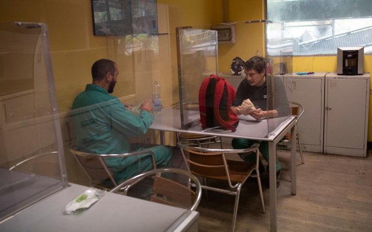 Trabajadores toman un receso en un cuarto con barreras de plexi vidrio en una fábrica de acero en Terni, Italia.