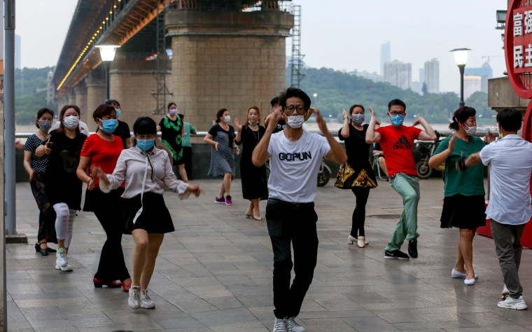 Personas con mascarillas bailan bajo el puente del río Wuhan Yangtze.