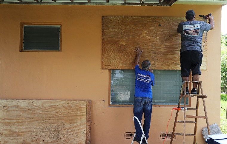 La gente pone shutters en las ventanas para preparar la casa de un familiae para el huracán Irma, en septiembre de 2017 en Miami, Florida.