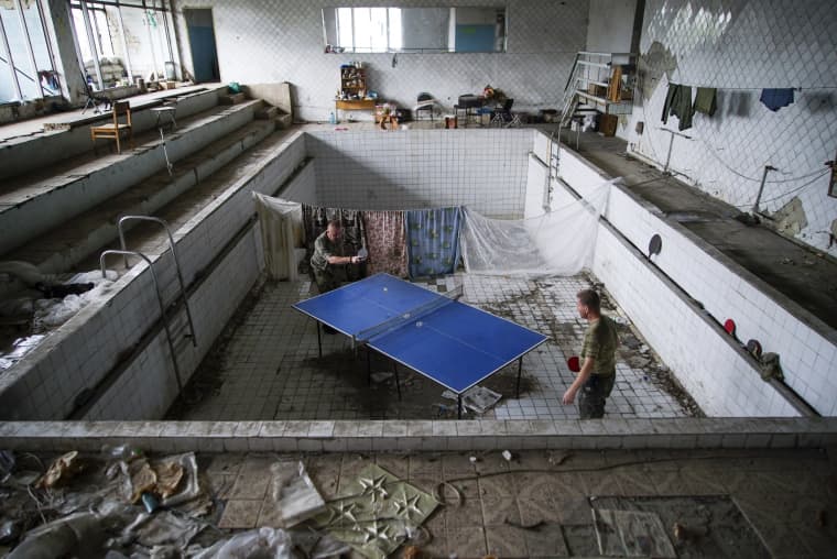 Image: Ukrainian soldiers play table tennis at a damaged swimming pool in the village of Marinka