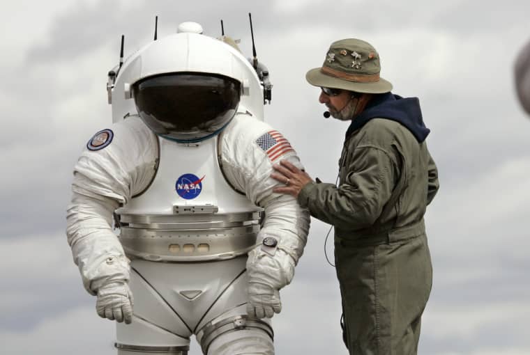 Technician Bill Welch, left, stands inside a 300-pound space suit as another technician talks with him June 10, 2008, in Moses Lake, Wash. NASA scientists and contractors spent two weeks in Moses Lake field testing some of the vehicles and robots that will be used when humans return to the moon later this century. (AP Photo/Elaine Thompson)