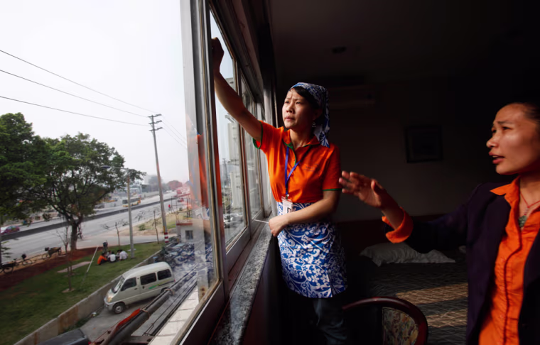 Image: Xiong Xuhua, left, is taught by her teacher how to use a squeegee to clean a window during a class at a school for domestic workers in China's southern city, Guangzhou.