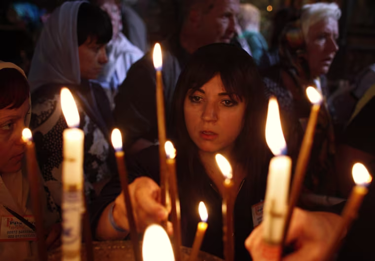 Image: A worshipper lights a candle in the Church of the Nativity in Bethlehem