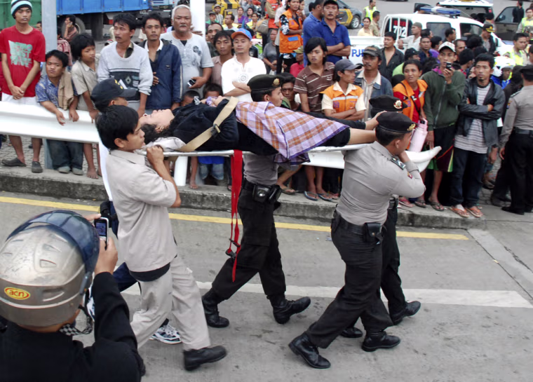 Image: Rescuers carry a ferry fire survivor at port