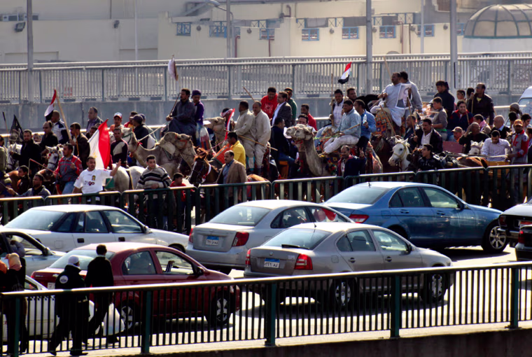 Image: Supporters of President Hosni Mubarak, some riding camels, march  in Cairo