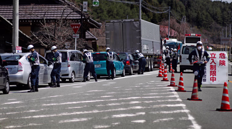Image: Police officers stop cars at a checkpoint near the town of Namie, inside the 20-kilometer (12-mile) evacuation zone, in Fukushima Prefecture, northeastern Japan