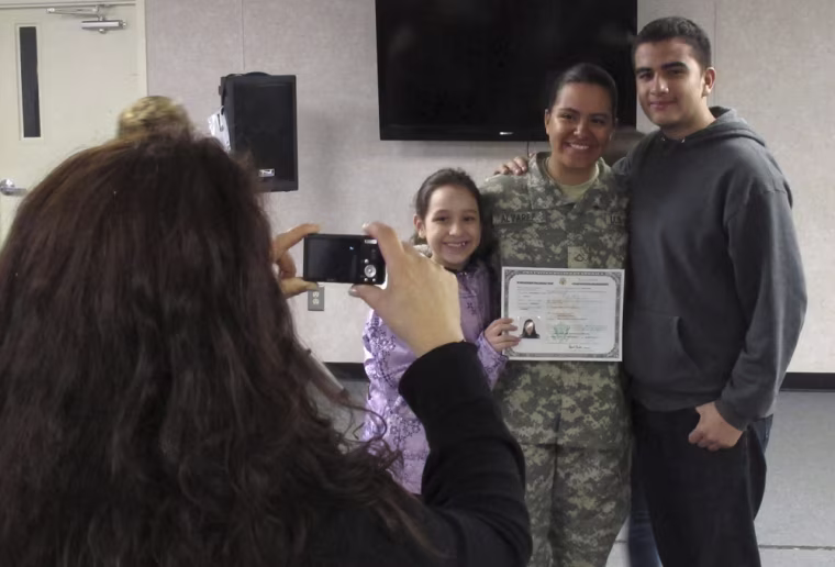 Image: Army Pfc. Jennifer Alvarez, center, of Colombia, poses with her family after taking the oath to become a U.S. citizen, at Fort Jackson, S.C.