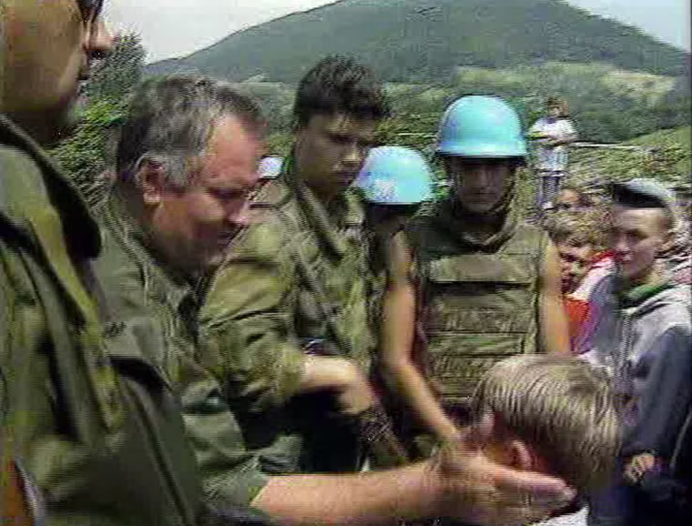 Image: Bosnian Serb boy Izudin Alic being patted on the head by a grinning Ratko Mladic in 1995