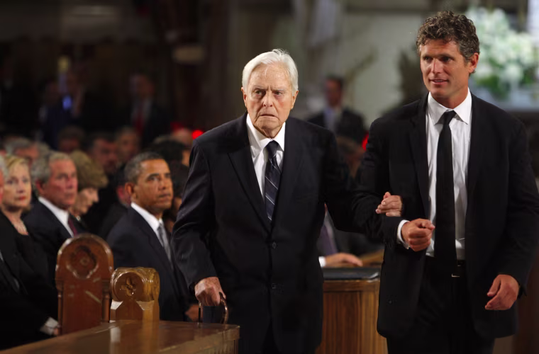 Image: Senator Edward Kennedy's brother in law Sargent Shriver is escorted to his seat in the church by his son Anthony Kennedy Shriver as U.S. President Barack Obama , former President George W. Bush and Secretary of State Hillary Clinton look on during