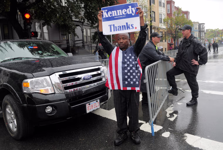 Image: Christopher Nzewwa, a native of Nigeria and longtime Boston resident, holds a sign thanking Senator Edward Kennedy
