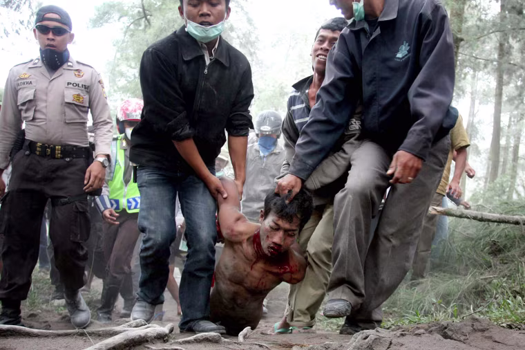 Image: Villagers escorted by police carry a sus