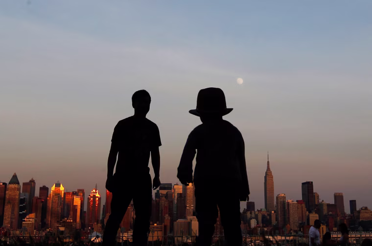 Image: A father and his son watch the moon rise over the skyline of New York from a lookout in Weekhawken, New Jersey
