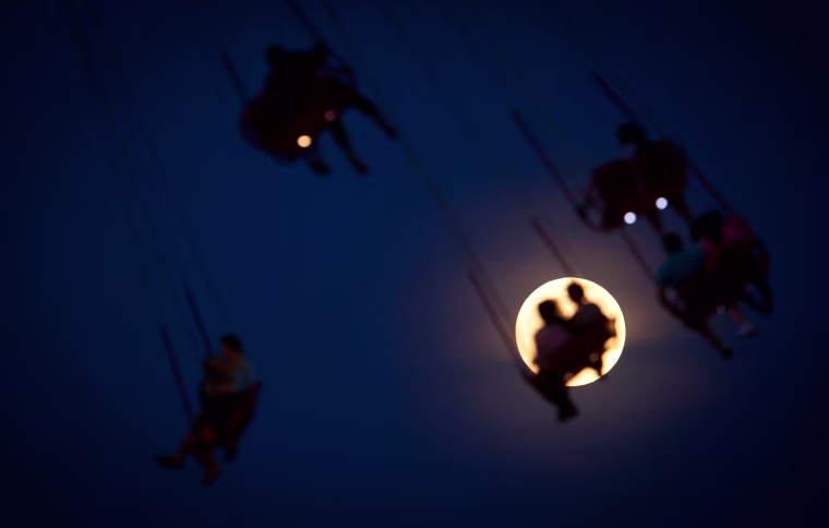 Image: People ride the Luna Park Swing Ride as the Super Moon rises on Coney Island