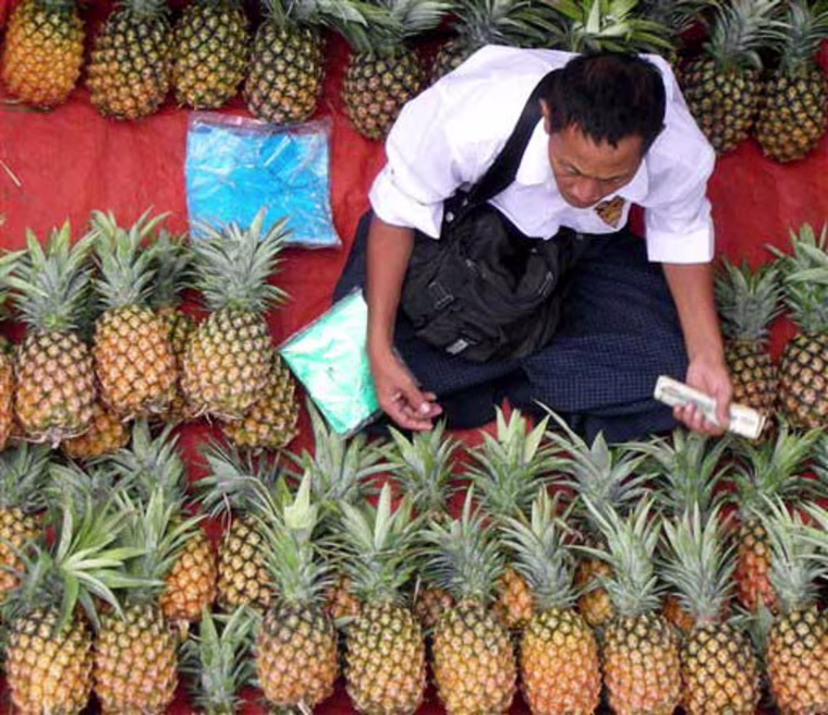 A man selling fresh pineapples waits for customers Saturday, July 5, 2008, in Yangon City, Myanmar. A variety of local cuisine as well as fruits and vegetables are sold on the city's sidewalks. Credit: AP Photo