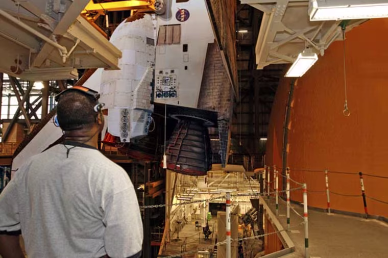 A worker watches as space shuttle Atlantis is carefully lowered so it can be anchored to the external tank in preparation for launch. Credit: NASA/Dimitri Gerondidaki