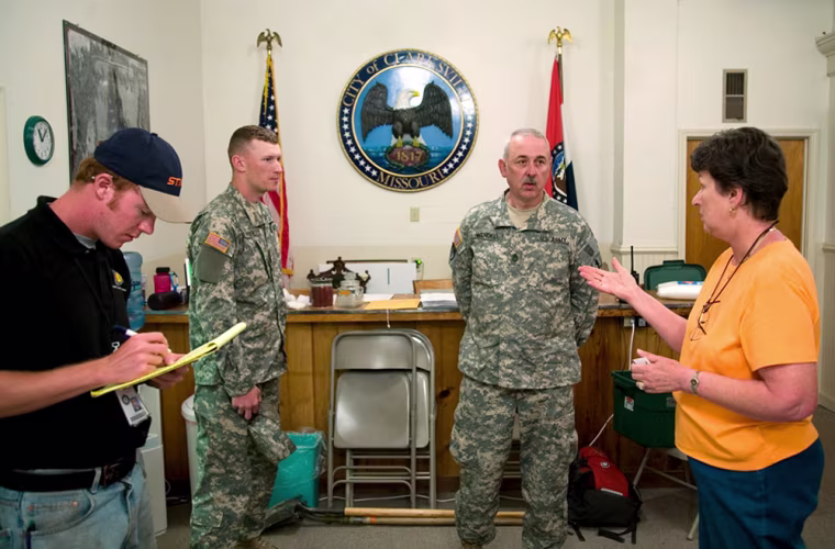 Mayor Smiley of Clarksville, Missouri, coordinates flood preparation with members of National Guard.