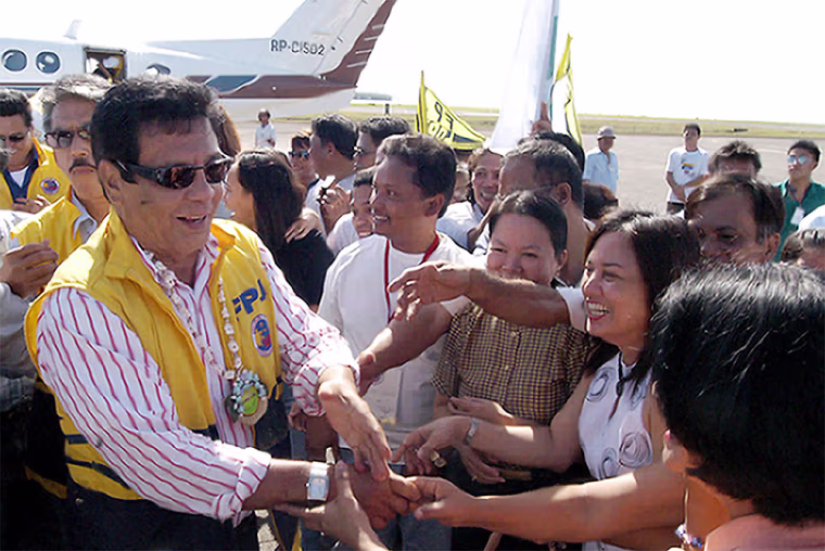 Philippine action movie star Fernando Poe (L) shakes hands with supporters during a campaign sortie in the central Philippine city of Tacloban, in Leyte province, 04 March 2004, as he moves to kick-start his flagging campaign after fighting off a damaging court case over his eligibility.  The Philippine Supreme Court 03 March allowed Poe to stand in the 10 May presidential election, dismissing petitions to have him disqualified on grounds of citizenship.    AFP PHOTO