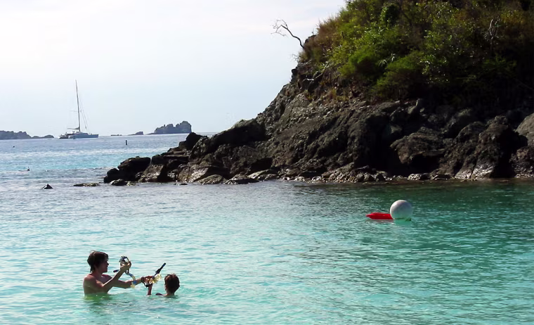 ** ADVANCE FOR SUNDAY, APRIL 18 AND THEREAFTER ** Swimmers don snorkeling gear, preparing to start on April 4 the National Park Service's only underwater snorkeling \"trail\" at Trunk Bay in Virgin Islands National Park on the island of St. John. The 650-foot trail of markers guides snorkelers past coral reefs along the edge of a small island. Buoys in the distance warn boats from entering the bay, dropping anchor or running aground on the reefs and seagrass beds. (AP Photo/John Heilprin)