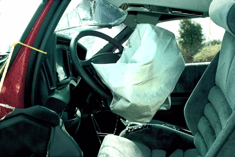 ** FILE ** A March 1990 file photo of deployed airbag in of of two Chrysler LeBarons that crashed head-on in Culpeper, Va. Twenty years ago this month, the government made a decision that saved 15,000 lives _ but killed 242 others. On July 11, 1984, then-Secretary of Transportation (no Senator) Elizabeth Dole issued a rule requiring vehicles to have driver's side air bags or automatic seat belts by 1989 and passenger bags soon after. (AP Photo/Department of Transportation, File)