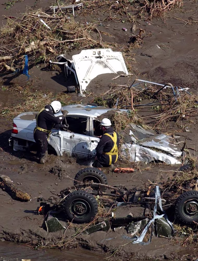 Workers from the emergency services examine vehicles in the Boscastle area of Cornwall, south west England, Tuesday Aug. 17, 2004, after a wall of water tore through the picturesque tourist spot on Monday. Emergency workers are checking for possible victims of the flooding which was sparked by 2.4 inches (6 centimeters) of rainfall in just hours on Monday afternoon. (AP Photo/Barry Batchelor/PA) ** UNITED KINGDOM OUT MAGS OUT NO SALES **