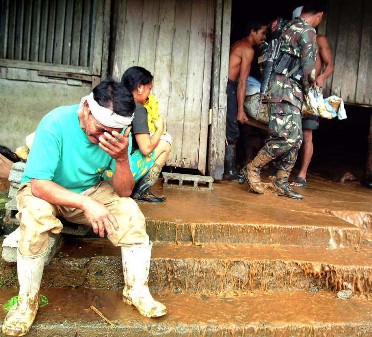 Filipino villagers retrieve the bodies of landslide victims in the mountains of Siera Madre