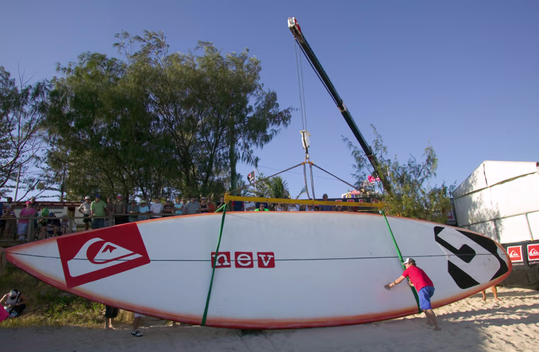In this photo released by the Association of Surfing Professionals, a 40-foot surfboard is hoisted on to the beach at Snapper Creek in Coolangatta, Australia, Saturday, March 5, 2004 during the Quiksilver Pro surfing tournament. The massive surfboard, shaped by Australia's Nev Hyman, took one month to build and will require 100 blocks of surfboard wax when it takes to the water with 45 of the world's best surfers on it's deck. The board will be used to raise funds for the victims of the recent Tsunami disaster when it travels to beaches around the world. (AP Photo/ASP, Pierre Tostee)