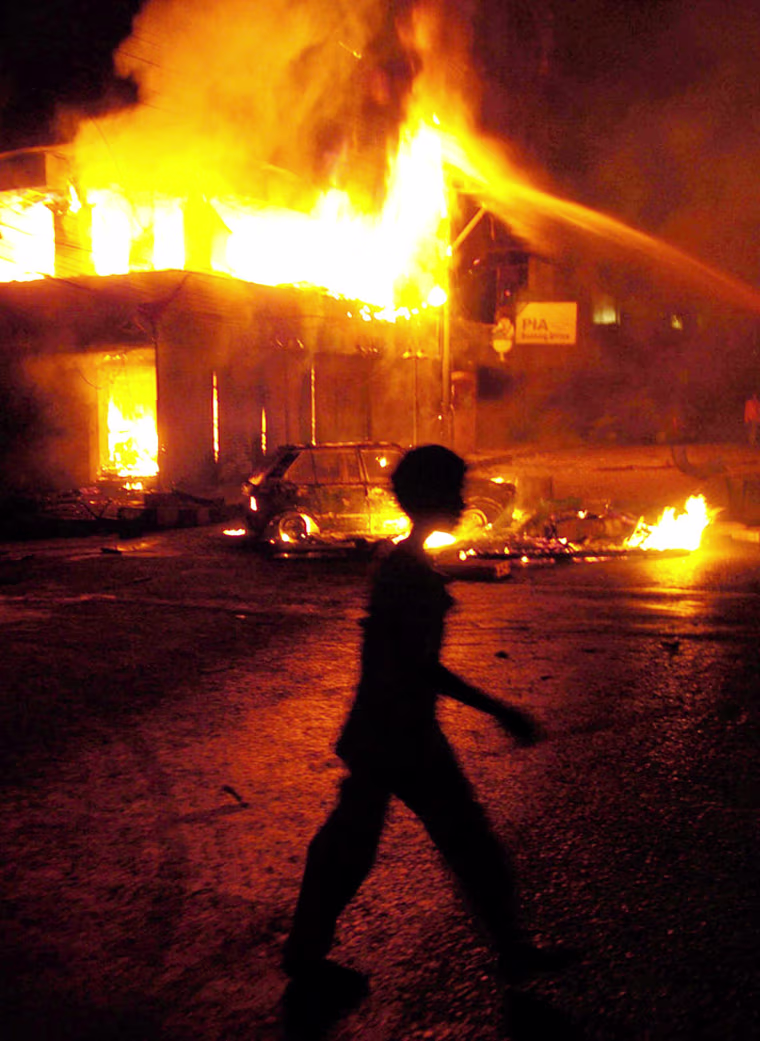 A Pakistani boy walks past a burning veh