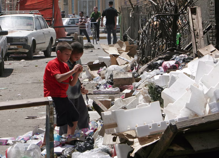 Children play next to a pile of rubish in a poor part of the Baghdad Sunni neighborhood of Azamiyah, Tuesday, Aug. 23, 2005. Sunnis, who dominated Iraqi society under Saddam, oppose decentralization in the new constitution, fearing it would cut them out of the country's oil wealth and leave them powerless. (AP Photo/Khalid Mohammed)