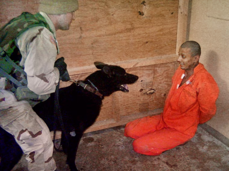 **FILE** This undated still photo made available by The Washington Post on Friday May 21, 2004, shows a U.S. soldier holding a dog in front an Iraqi detainee at Abu Ghraib prison on the outskirts of Baghdad.  (AP Photo/The Washington Post)
