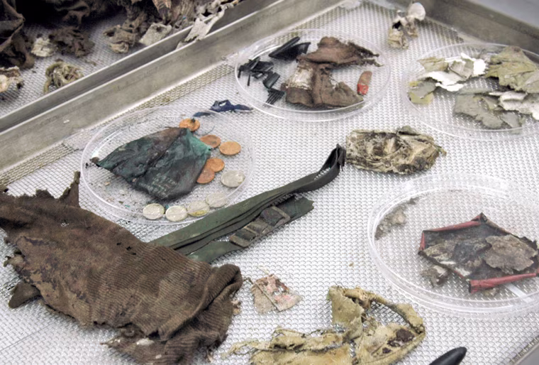 *** FILE *** Articles of clothing, coins and paper, found among the remains of a serviceman from World War II are shown on the examination table of the autopsy room at Joint POW/MIA Accounting Command (JPAC) at Hickam Airforce Base in Honolulu, Hawaii, Tuesday, Nov. 8, 2005. The World War II airman, now identified as Leo Mustonen,  whose body was found on the California mountainside more than 60 years after his plane crashed will be buried in his central Minnesota hometown on Friday March 24, 2006. (AP Photo/Lucy Pemoni)