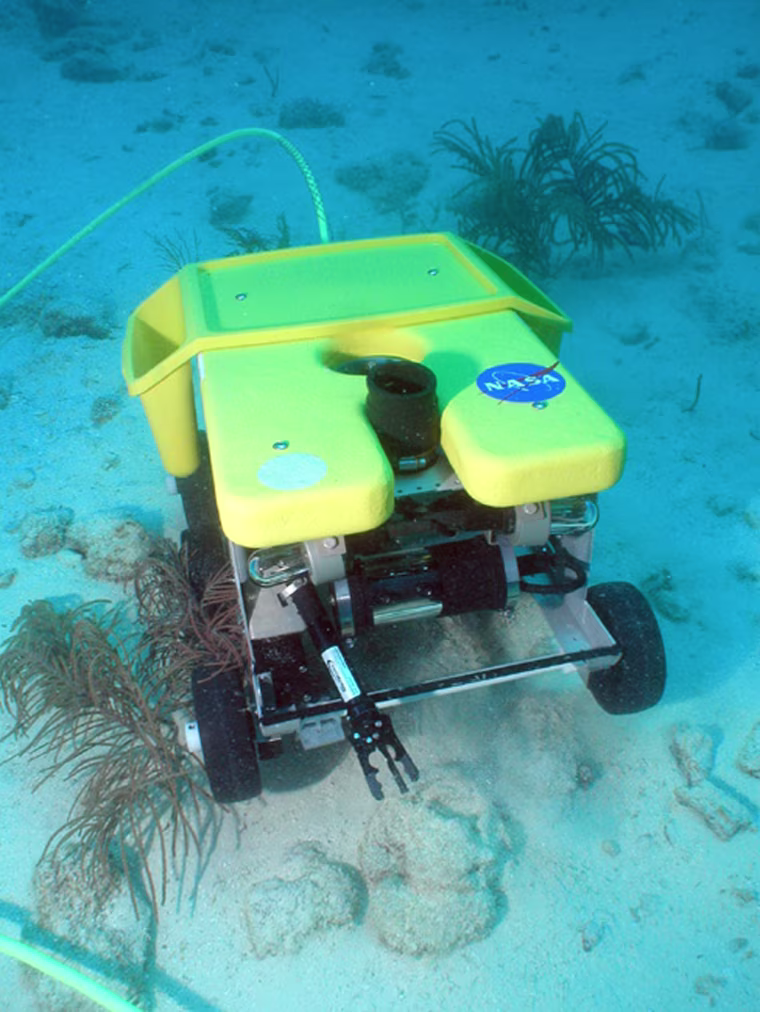 The Scuttle rover rolls along the ocean floor to collect samples and return them to the Aquarius Undersea Laboratory during NASA's NEEMO 9 mission.