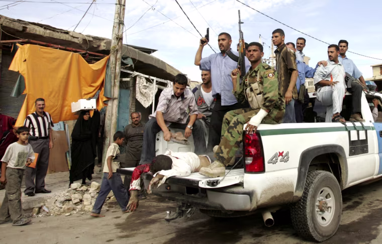 A man killed by gunmen lies in the back of a police vehicle in Baghdad