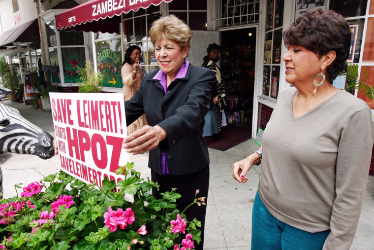 ** ADVANCE WEEKEND APRIL 28-29 ** Jackie Ryan, left, and sister Mary Kimbrough,co-owners of Zambezi Bazaar, adjust a sign in front of their store in Leimert Park Village section of Los Angeles, April, 6, 2007. The sisters believe the city is trying to replace black businesses in Leimert with those catering to wealthier white customers to boost tax revenues. Since 1991, their store has sold everything from old copies of Negro Digest, the predecessor to Ebony magazine, to earrings and statues from Africa. (AP Photo/Kevork Djansezian)